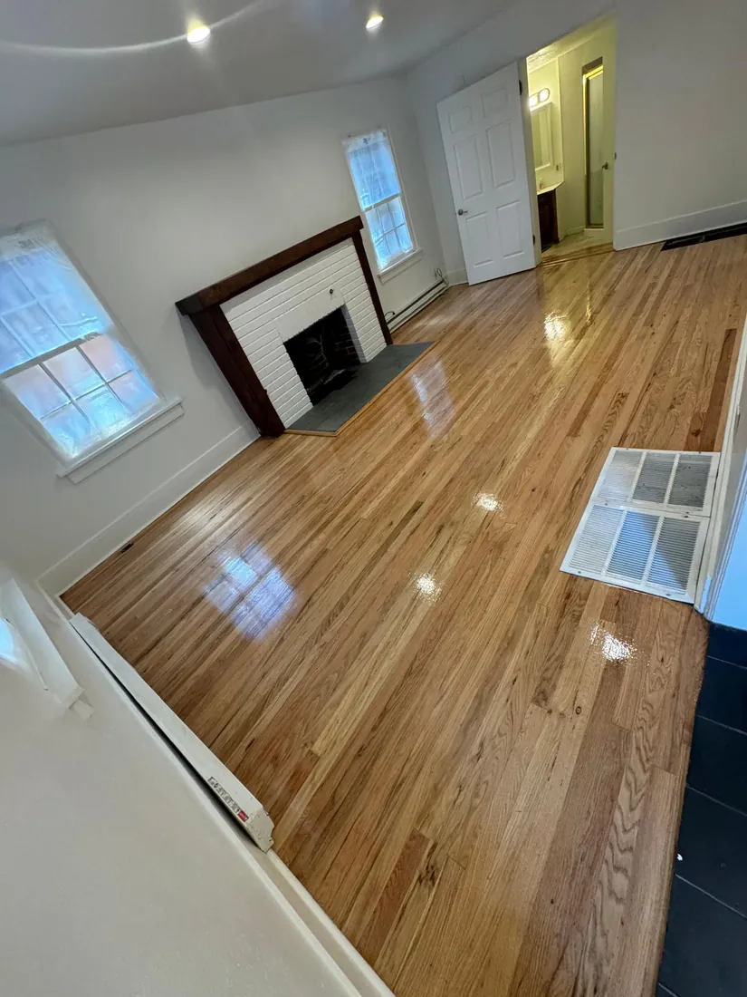 Refinished oak floor reflecting light across a living room with a white brick fireplace